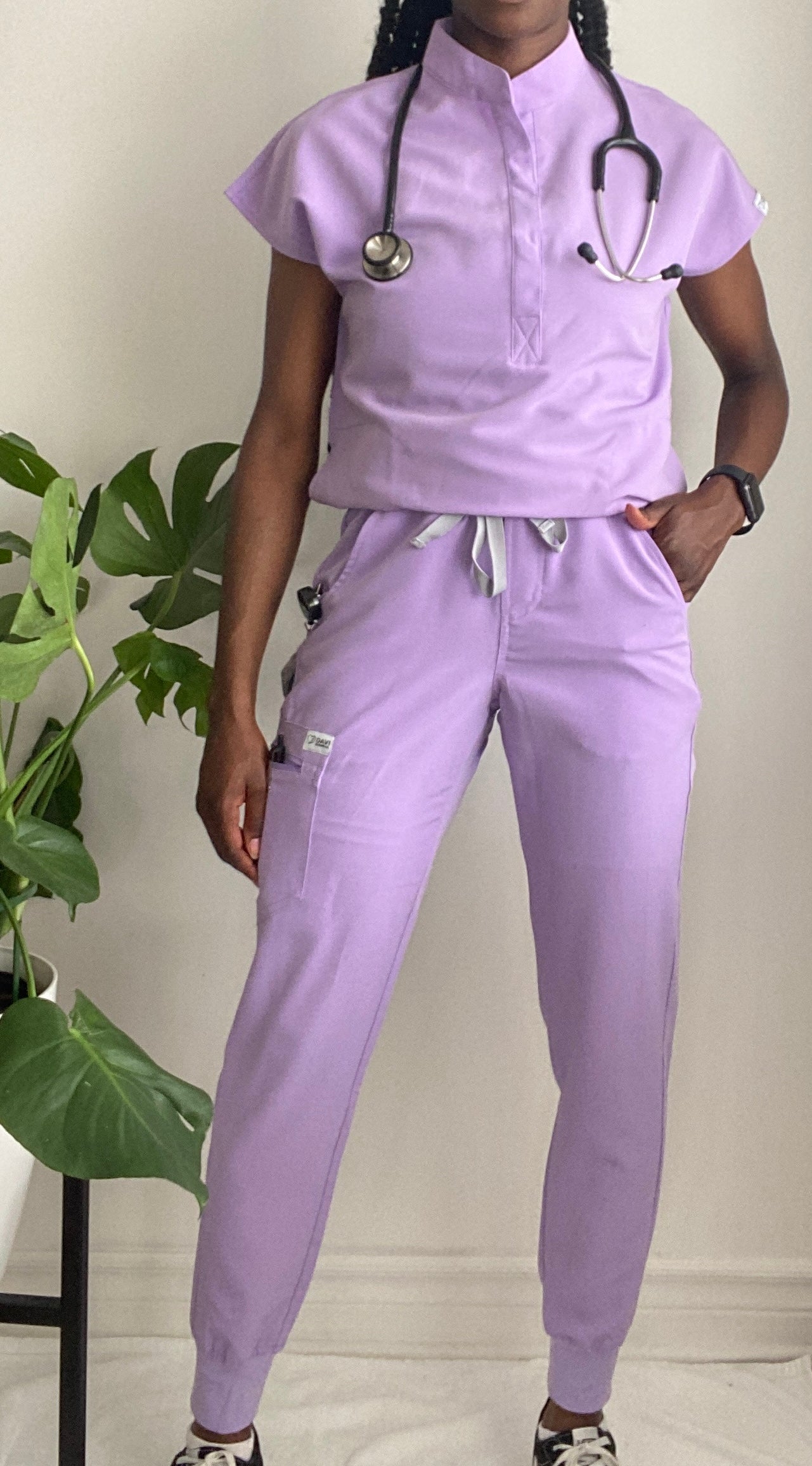 Haut d'uniforme avec deux poches discrètes à la taille, un col mao et un ourlet en pan de chemise. Couleur Lilas